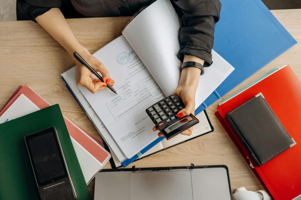 Small business owner reviewing financial documents and loan paperwork at a desk with a laptop displaying growth charts, representing common funding mistakes and financing decisions for businesses in 2026.
