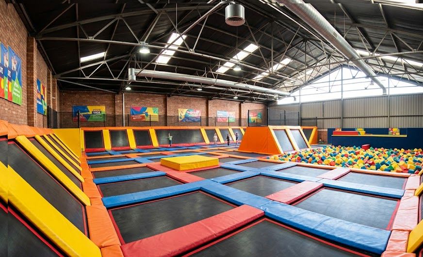 Interior of an indoor trampoline park with connected jump courts and foam pit, representing startup costs.
