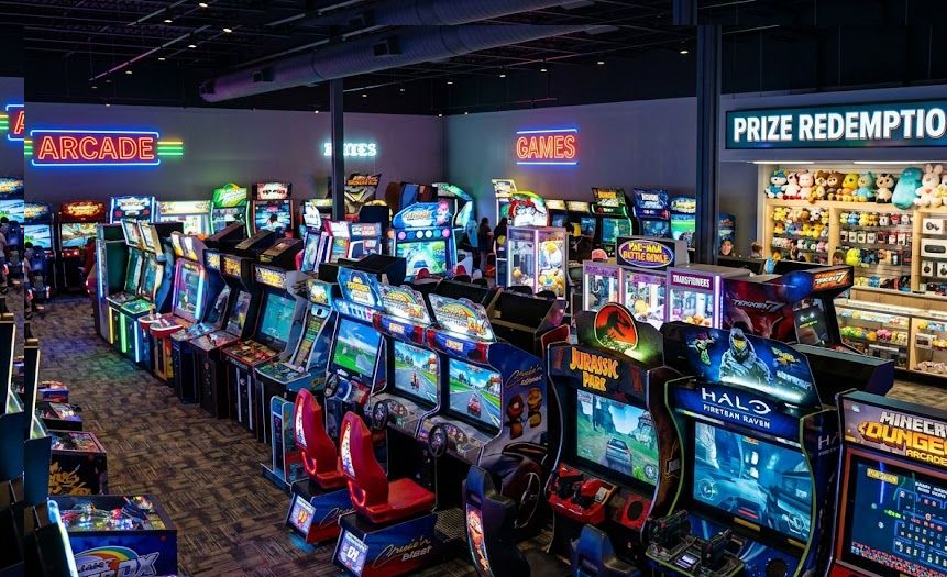 Interior of a modern arcade with rows of game cabinets and lights, representing arcade startup costs.