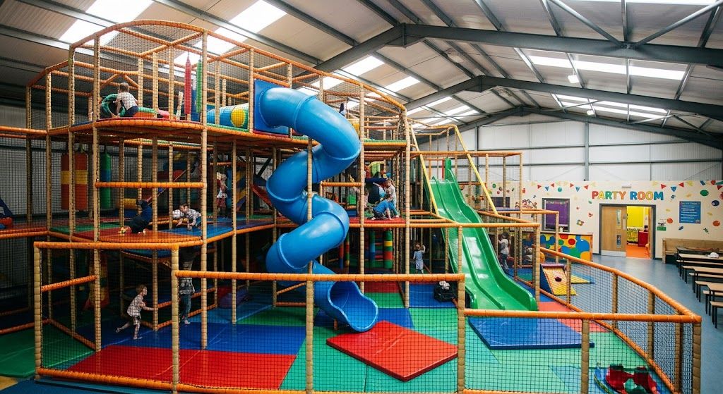 Interior of an indoor playground with a multi level soft play structure and safety flooring, representing startup costs.